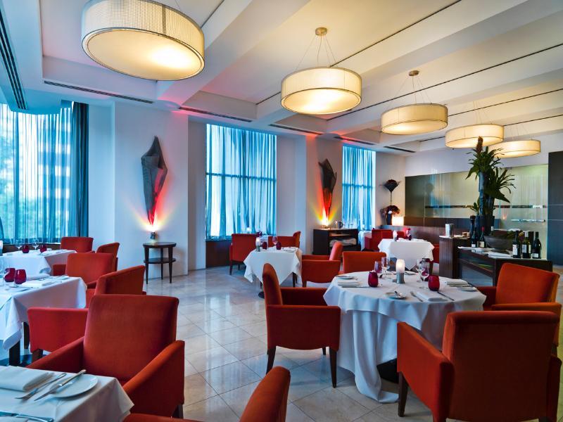 Amora Hotel Jamison Sydney Zewnętrze zdjęcie The photo shows an elegant restaurant interior. The space features stylish red chairs arranged around white tablecloth-covered tables. There are decorative elements like sculptures or artworks on the walls, and large windows covered with sheer curtai